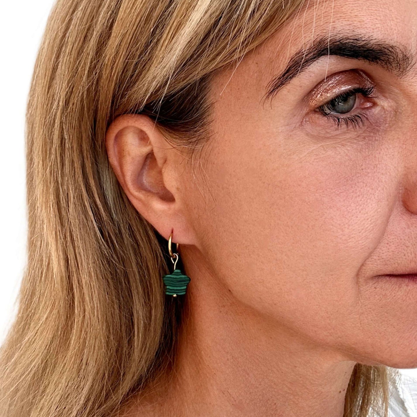gold hoop with green star charm worn on woman