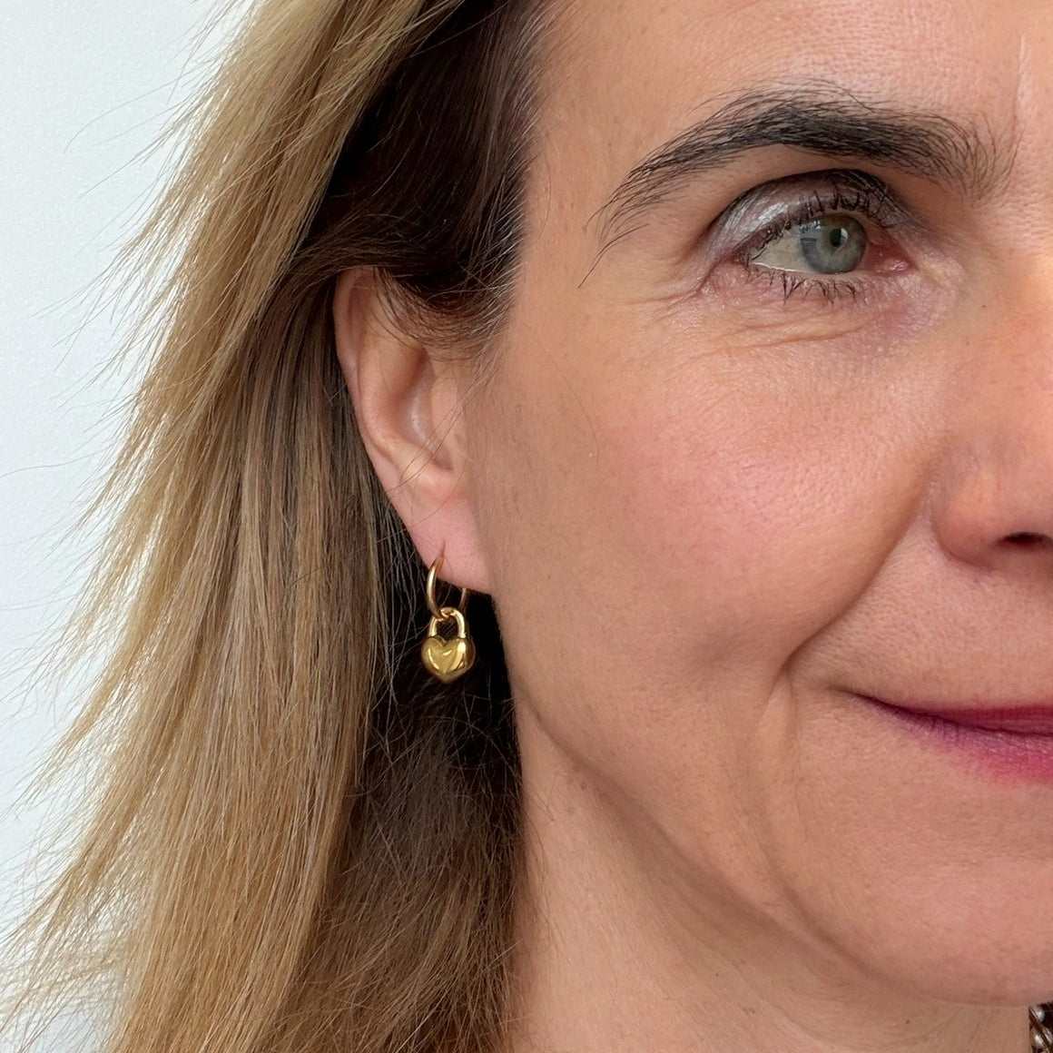 Close-up of a woman wearing a gold heart-shaped earring.