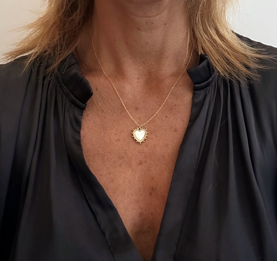 wearing necklace with heart shaped mother of pearl and gold charm 