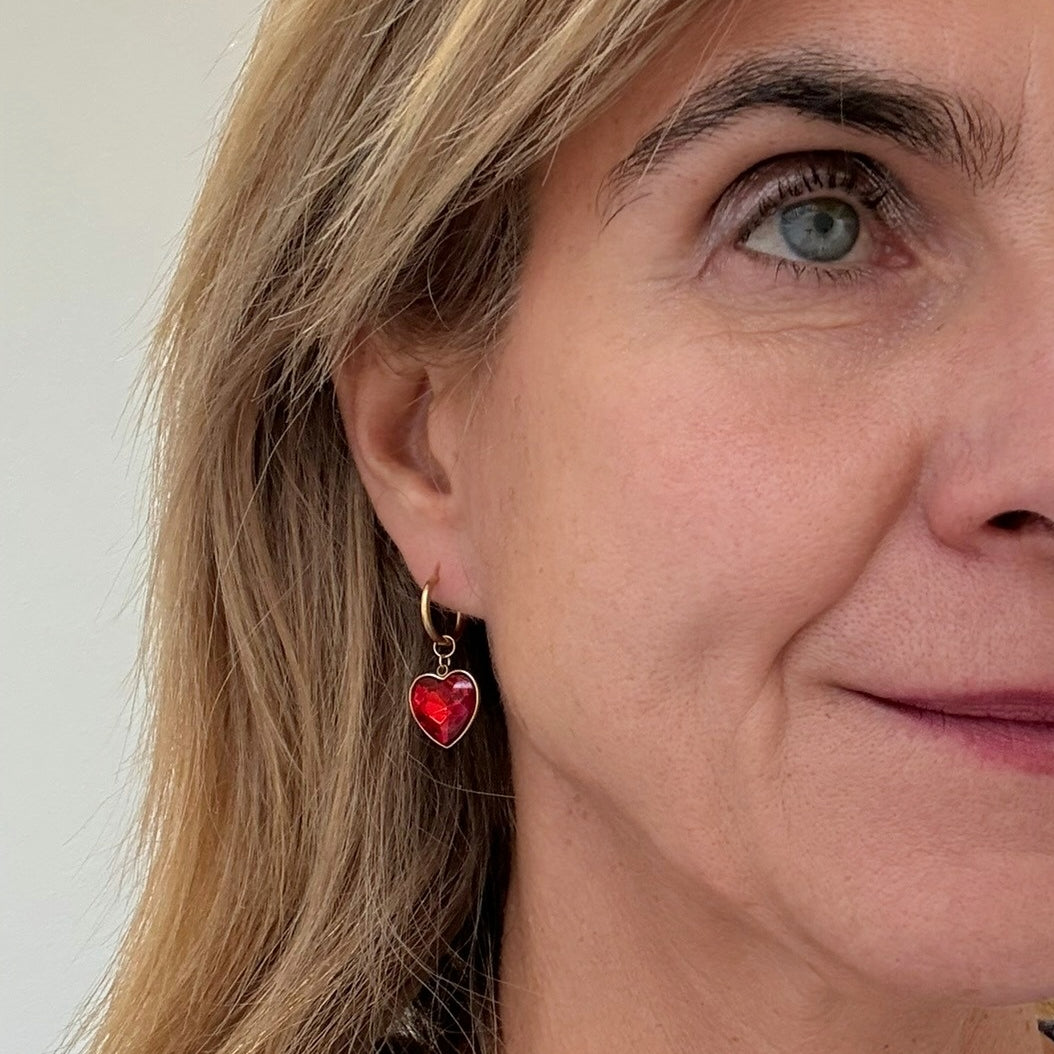 Delicate gold hoop earrings with red crystal heart charms