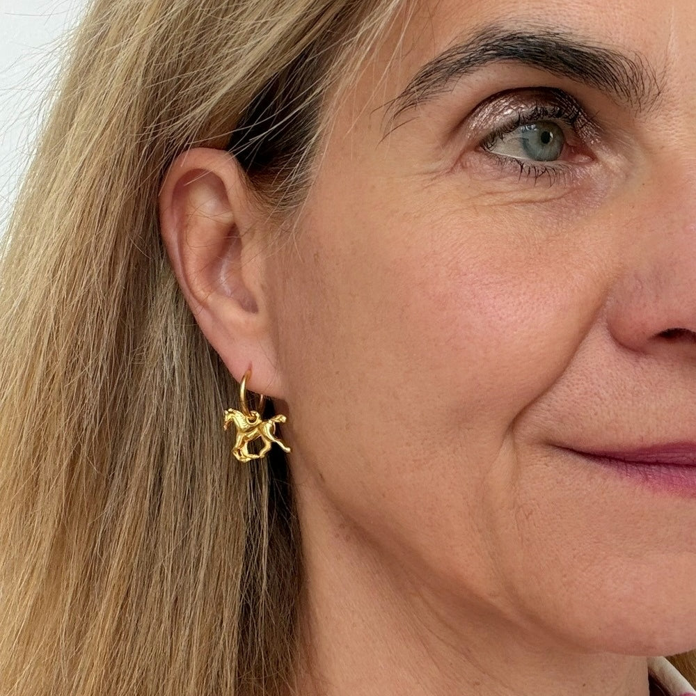 woman wearing gold hoop earrings with galoping horse charms