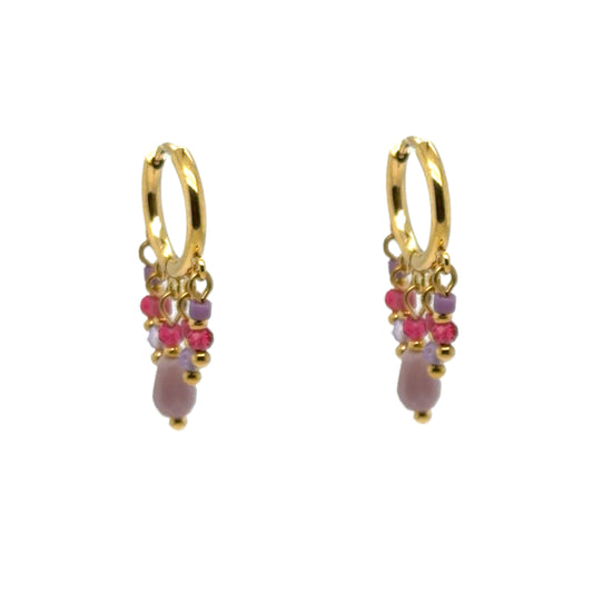 Huggie gold hoop earrings with small pink and purple crystal charms