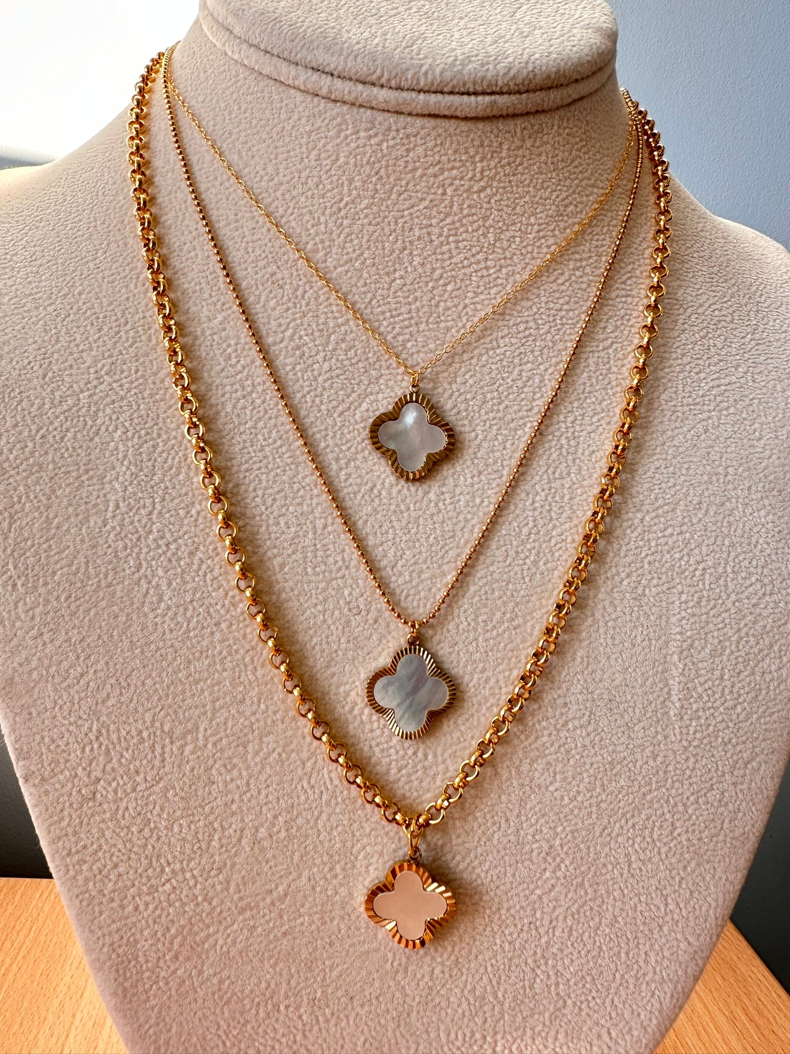 three necklaces with mother of pearl and gold clover charm pendants