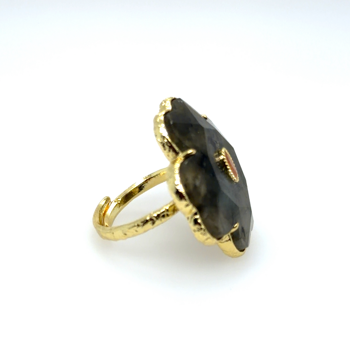 A gold ring with a large, irregularly shaped dark gray stone, photographed on a clean white background.