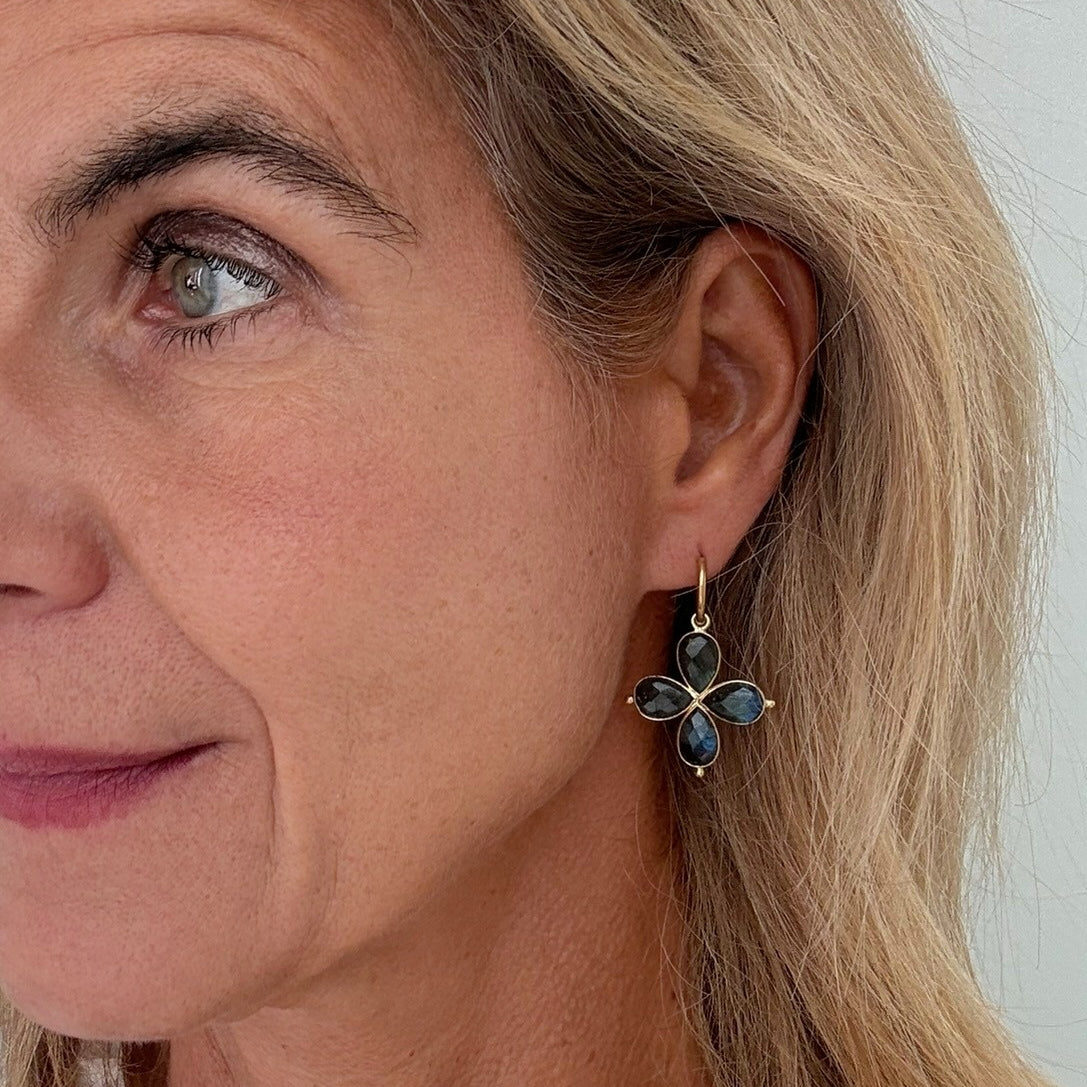 Close-up of a woman wearing a floral earring with labradorite gemstones.