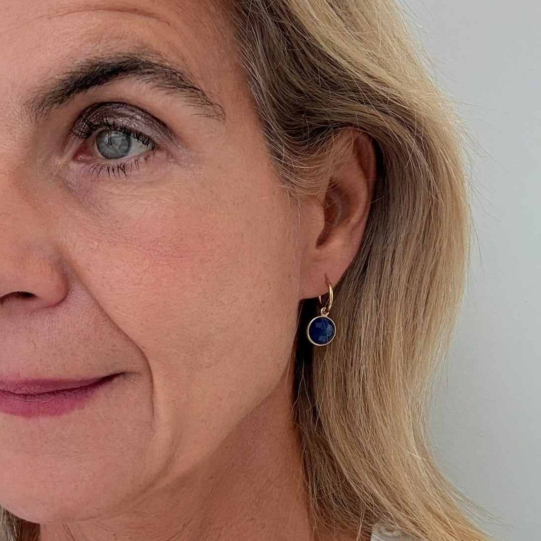 gold hoops with small blue round Lapis Lazuli charms worn on woman
