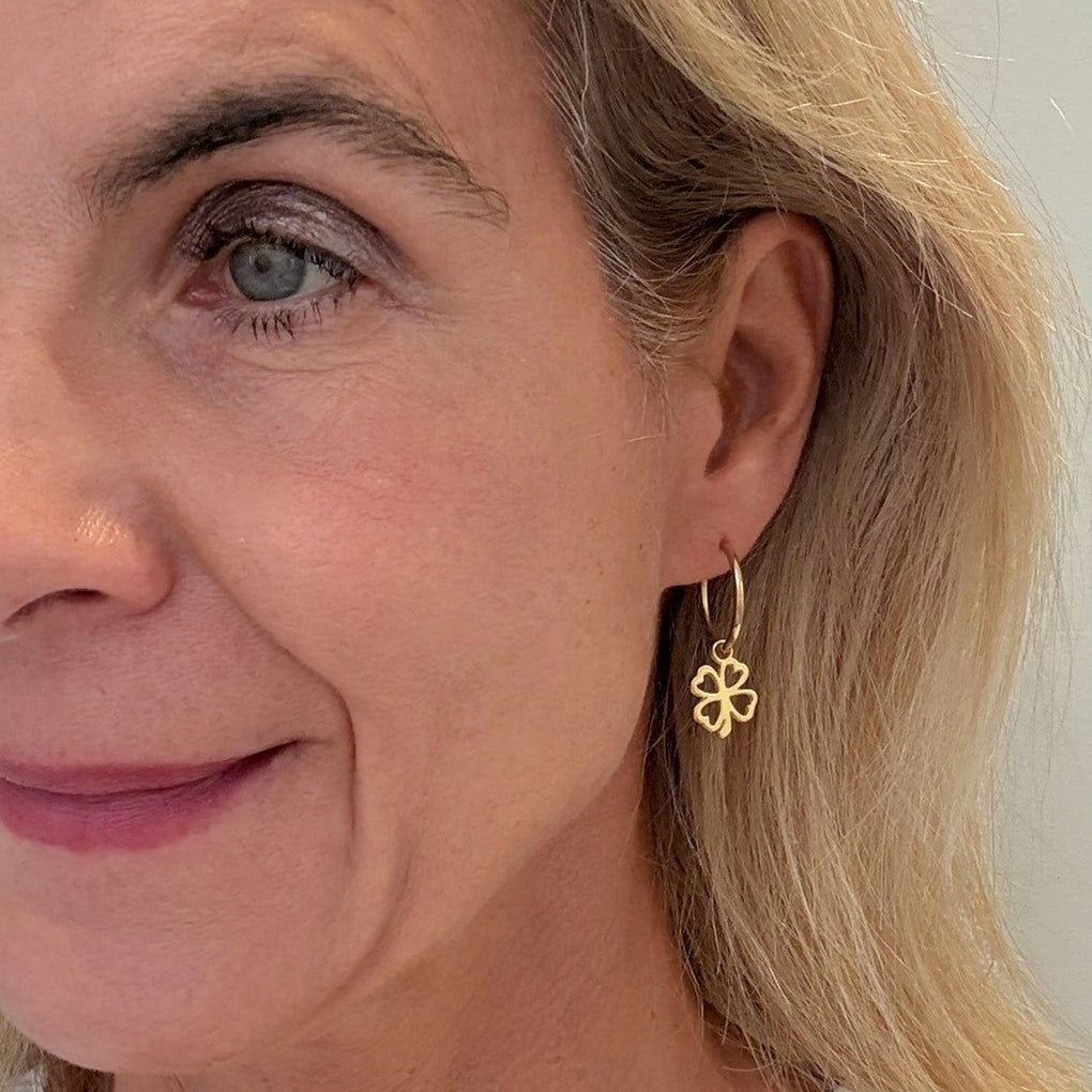 Close-up of a woman wearing a gold earring with a floral design.