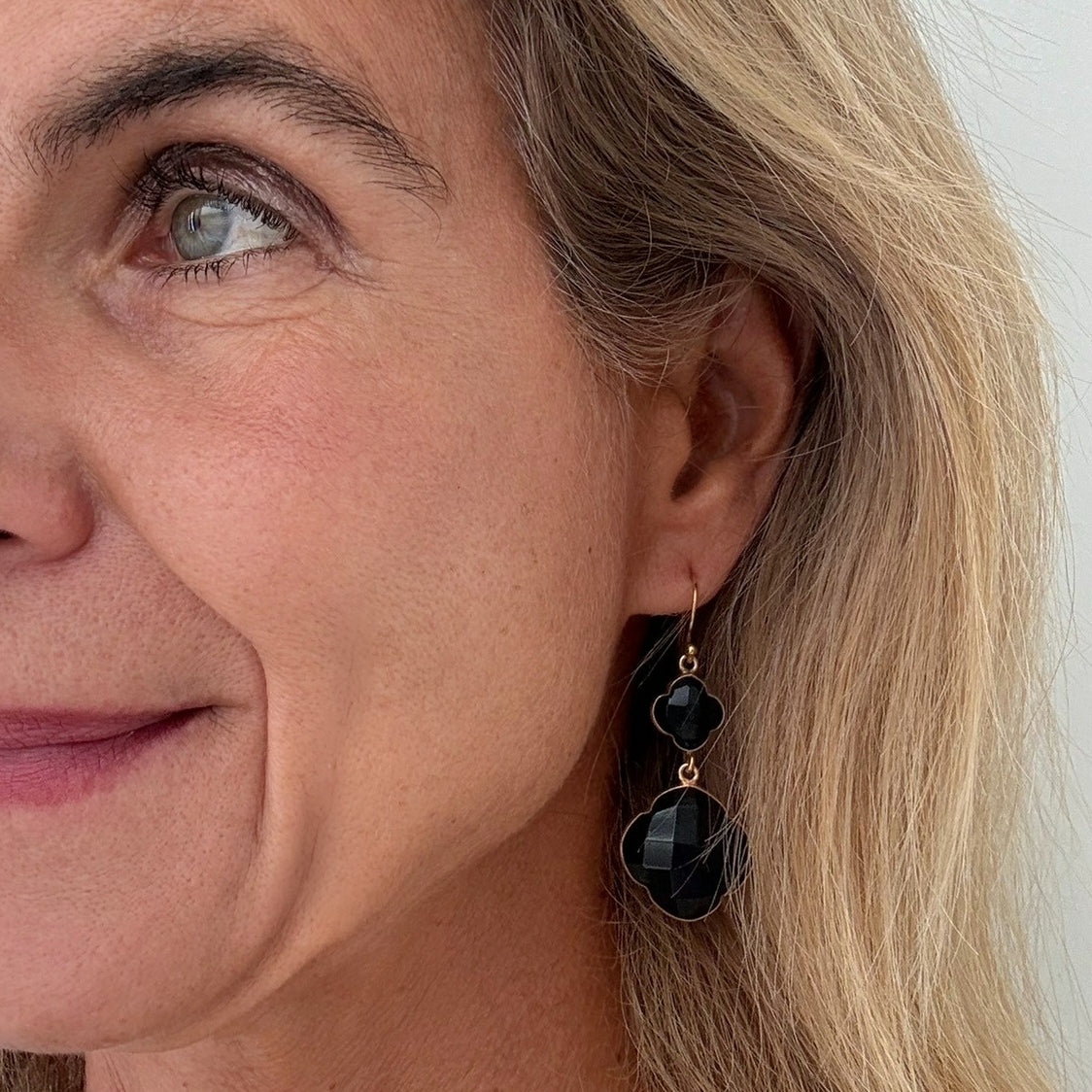 Close-up of a woman wearing black earrings with gold accents.