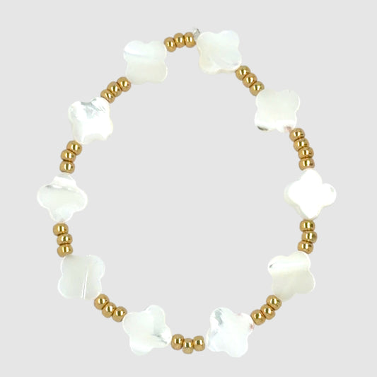 This stretchy bracelet has an alternating pattern of white mother of pearl clovers and three gold beads