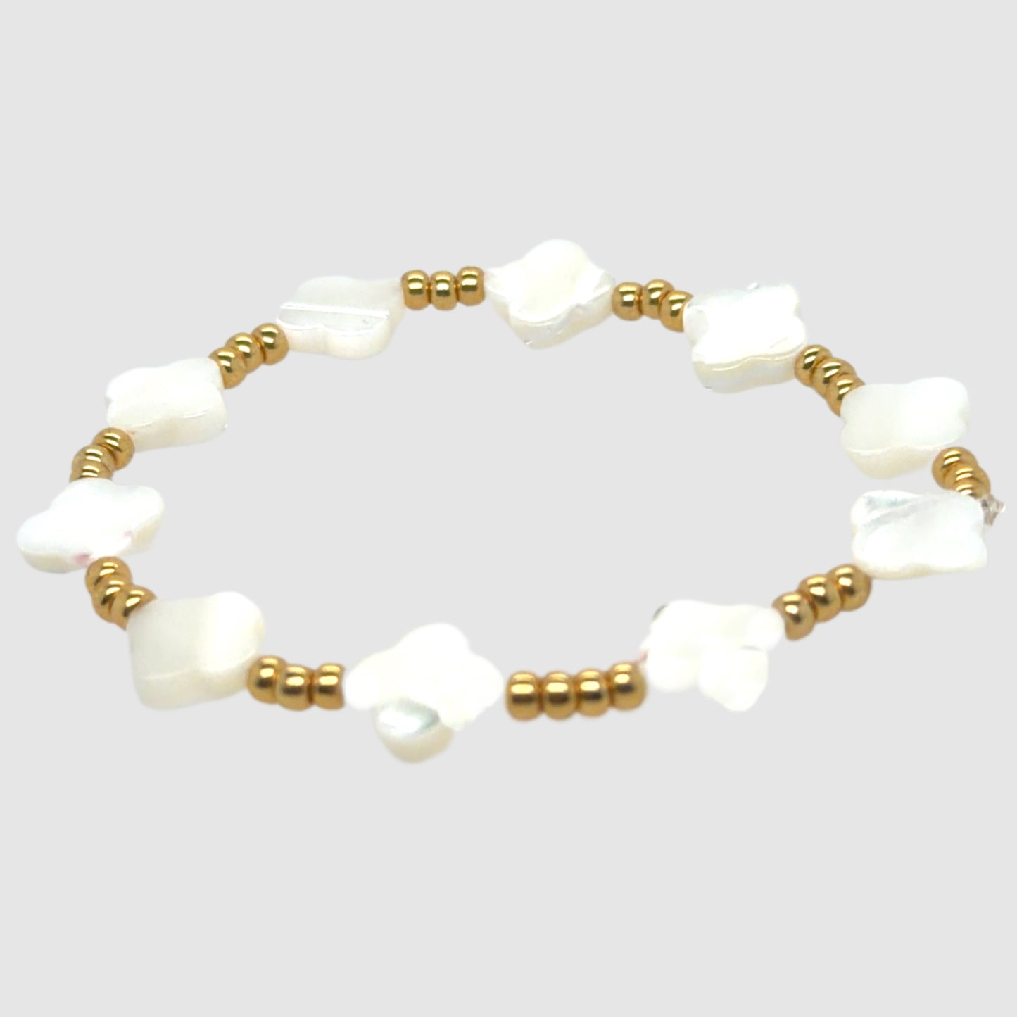 Pearl bracelet with gold beads on a light gray background