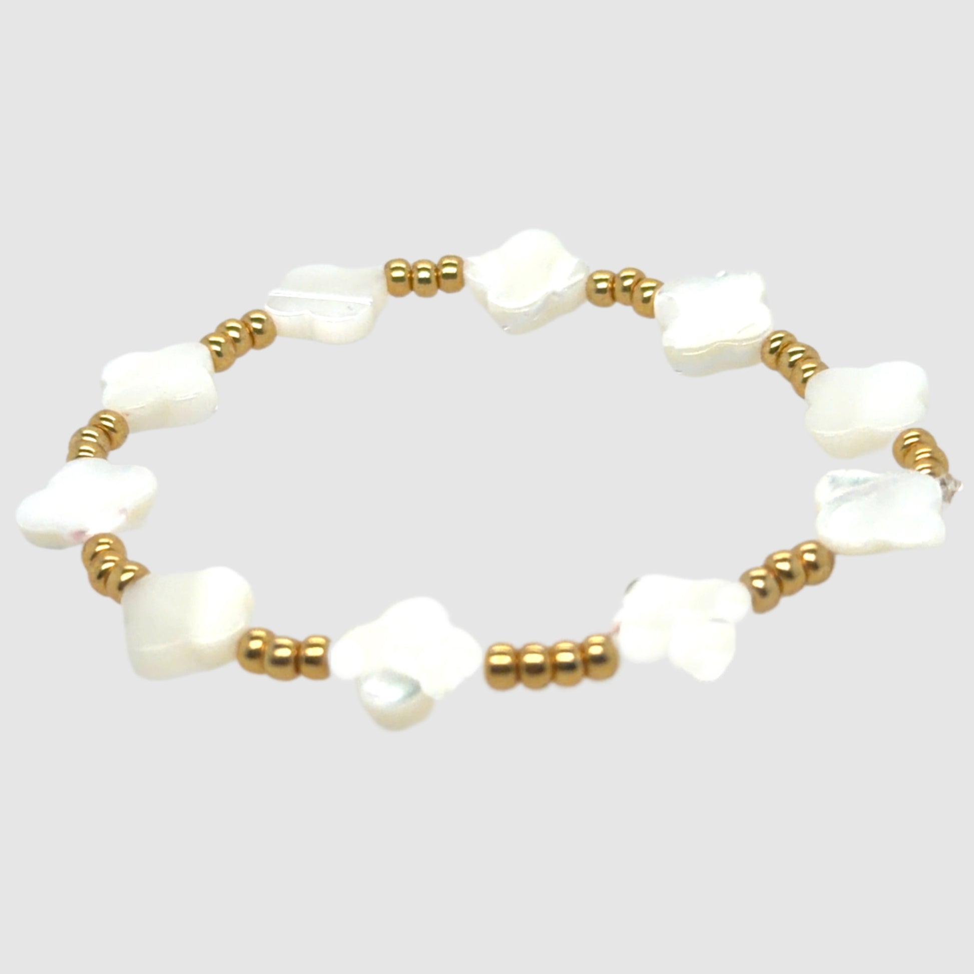 Pearl bracelet with gold beads on a light gray background