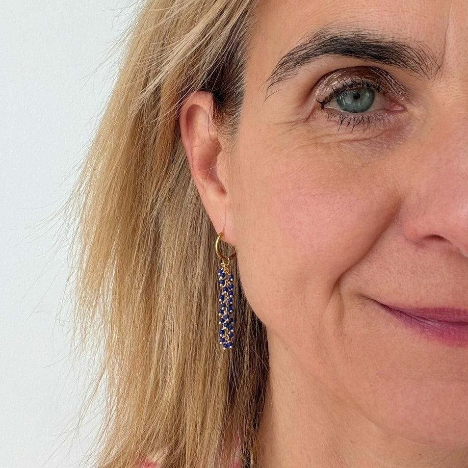 woman wearing dangling blue and gold hoop earrings