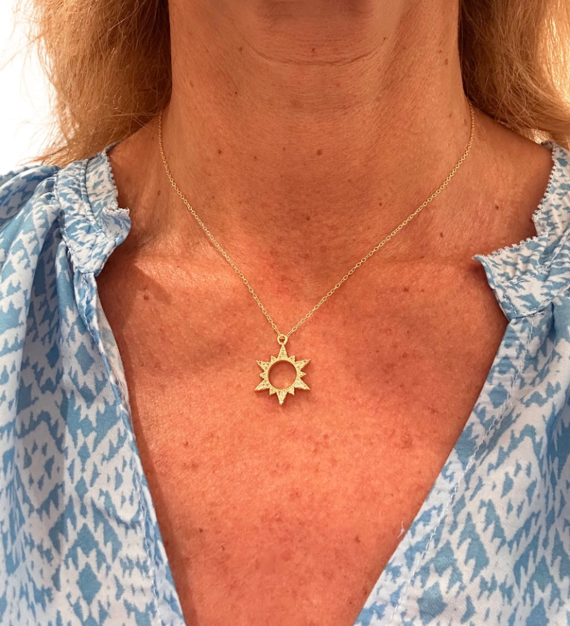 Delicate gold chain necklace with sparkly sun shaped charm