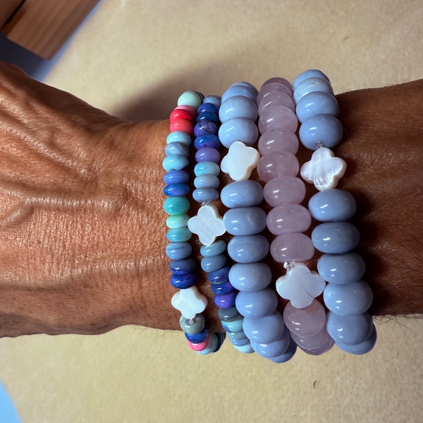 Wrist wearing multiple beaded bracelets with star-shaped charms on a neutral background