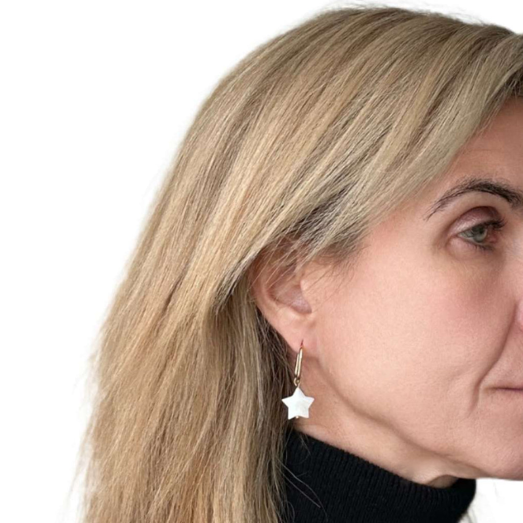 Close-up of a woman wearing a star-shaped earring on a white background
