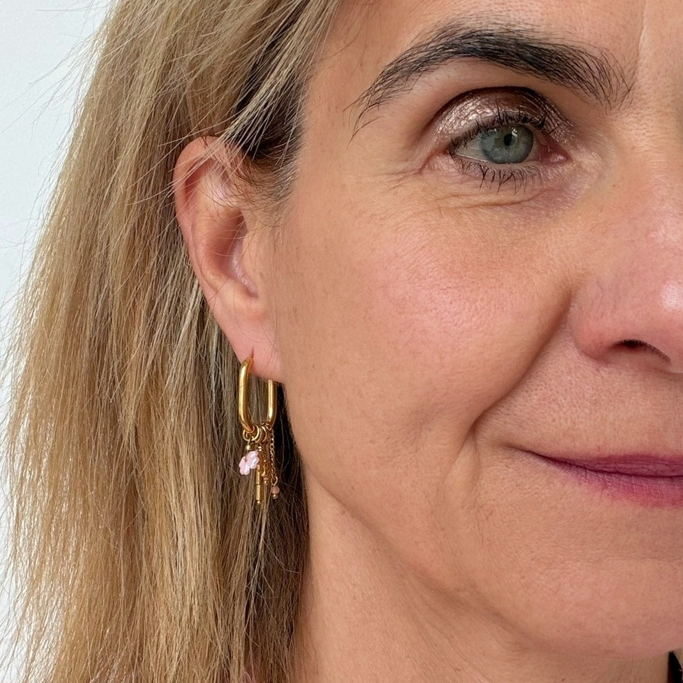 woman wearing oval hoop earrings with  dangling charms