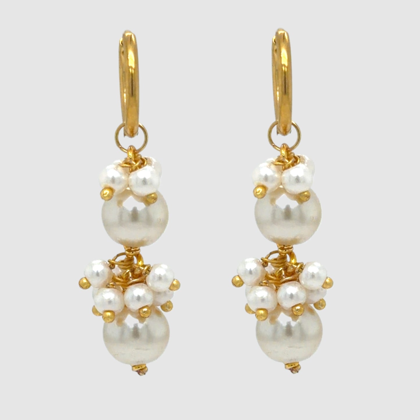 Pair of pearl earrings with gold accents on a light gray background