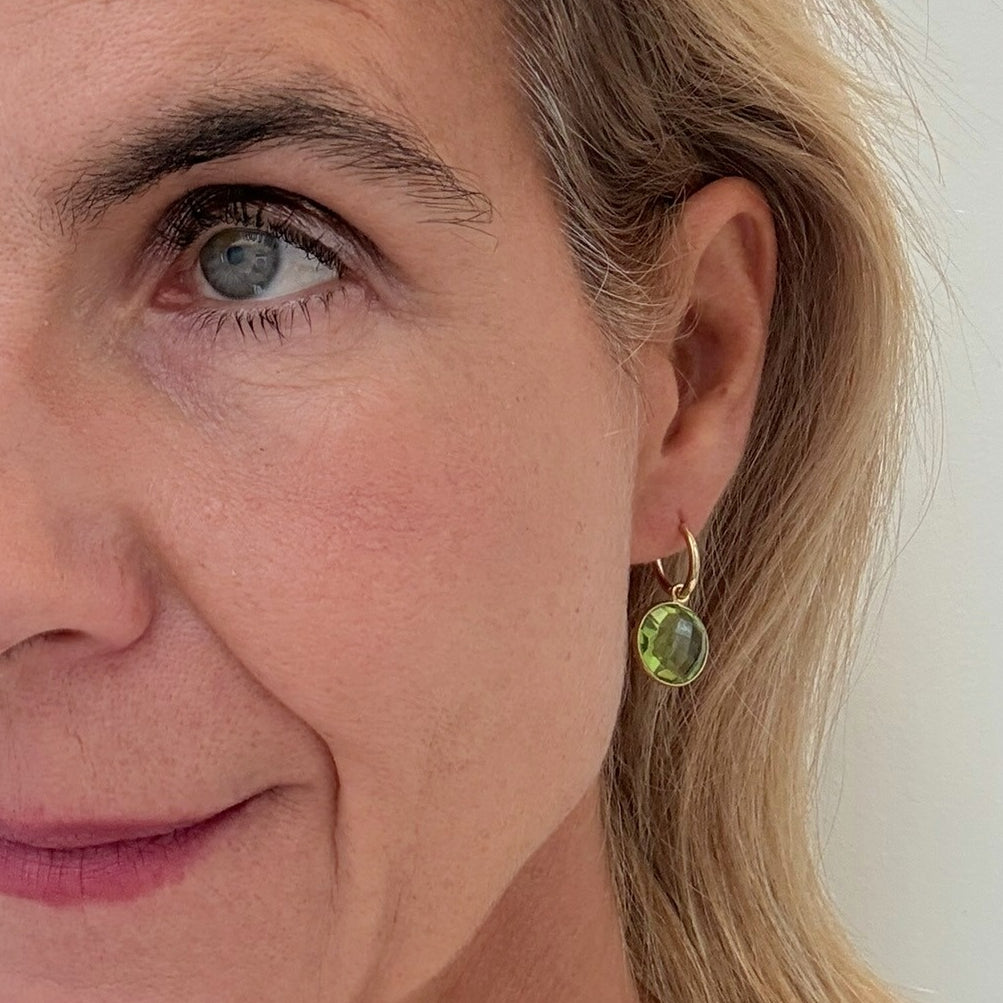 Gold hoop earrings with Peridot  gemstone round charms worn on model