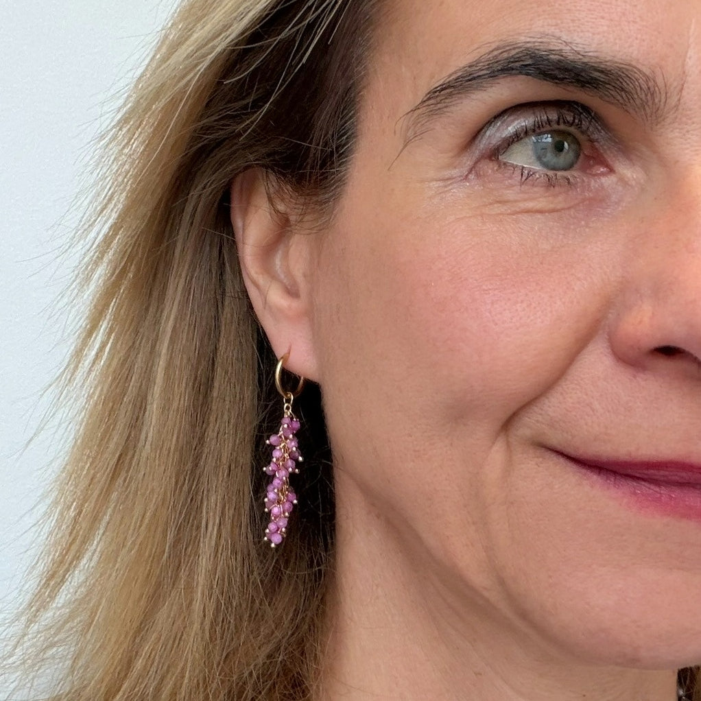 Close-up of a woman wearing pink earrings with a neutral background