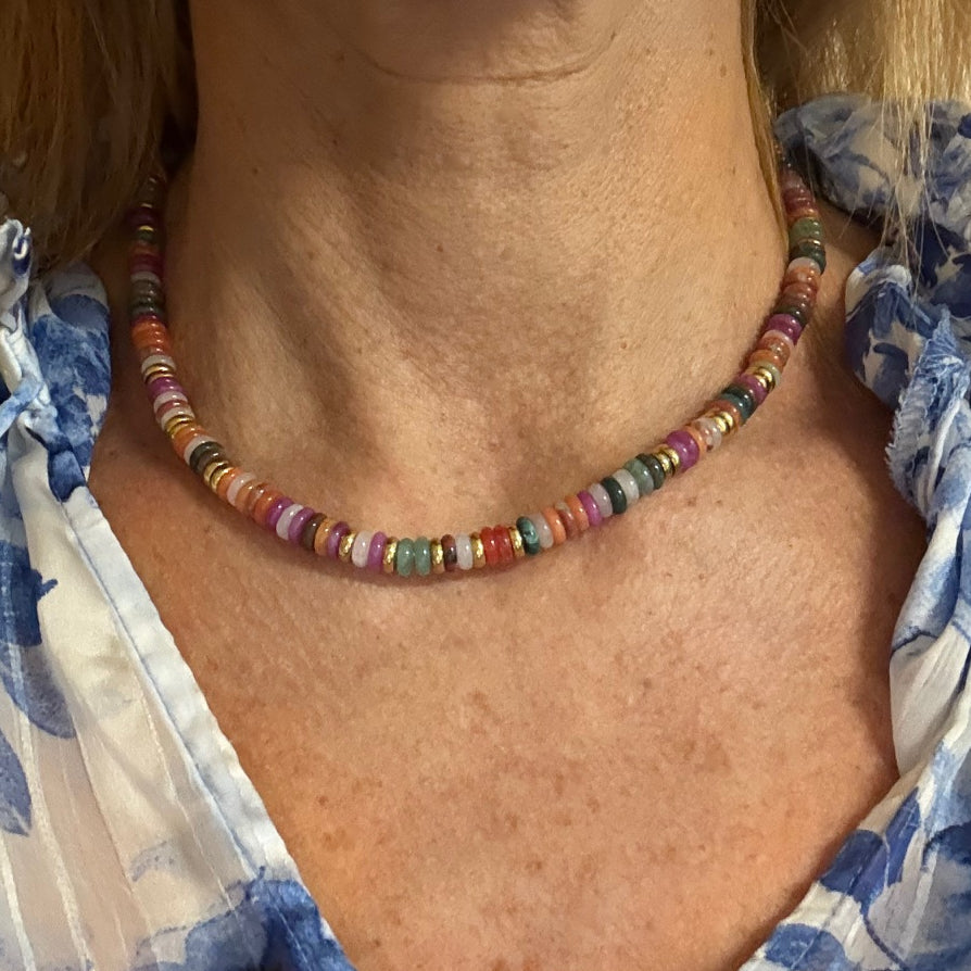 Woman wearing necklace with rainbow/ and gold rondelle beads. 