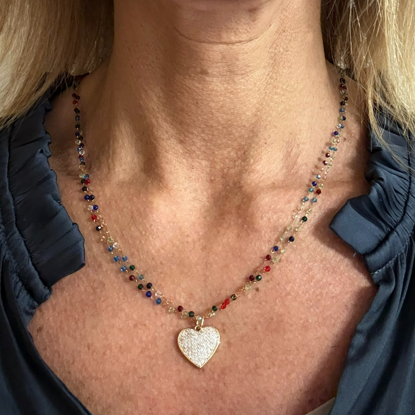 A model wearing a heart-shaped pendant necklace with multicolored beads