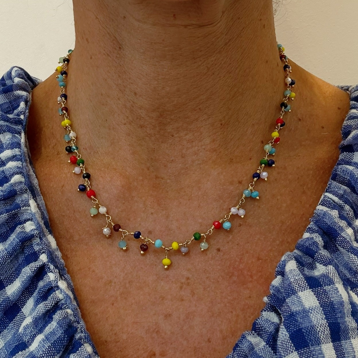 Rosary necklace with a rainbow of dangling quartz stones with gold wprn on model
