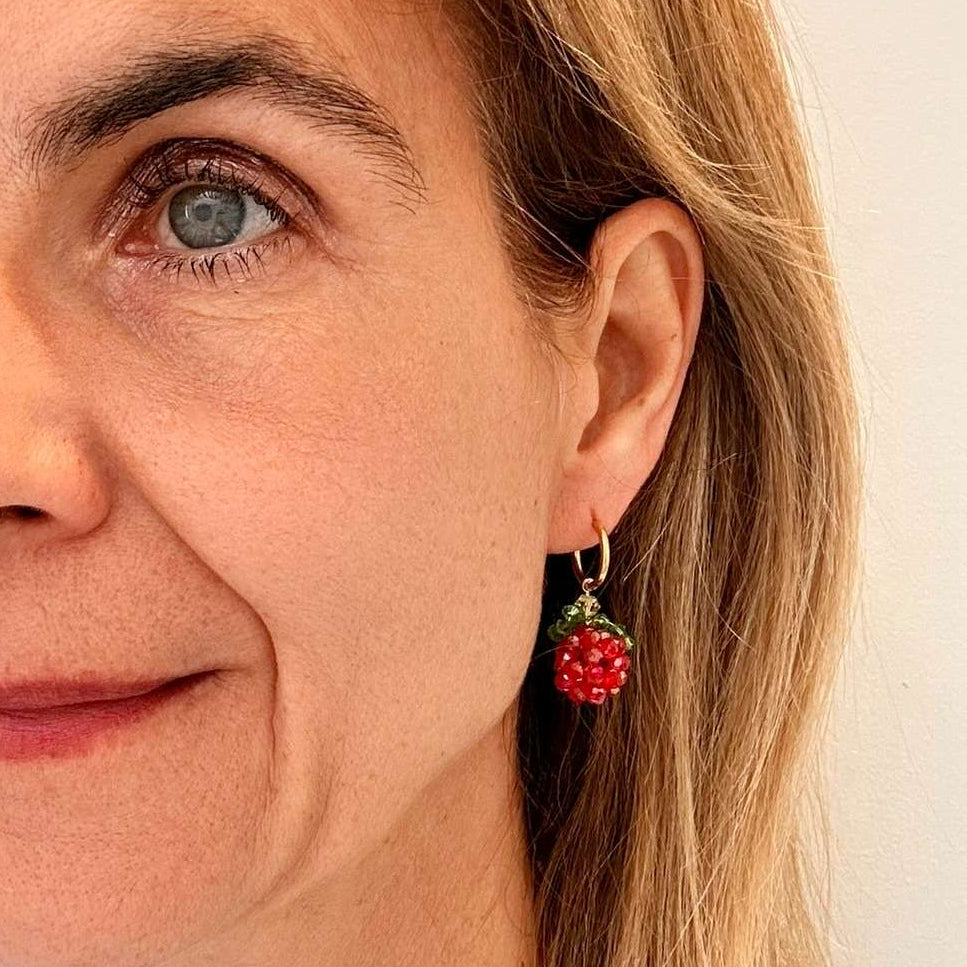 Delicate gold hoop earrings with raspberry beaded charms worn by model