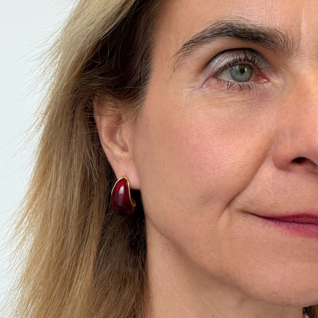 Lovely red and gold rounded teardrop earrings on a woman