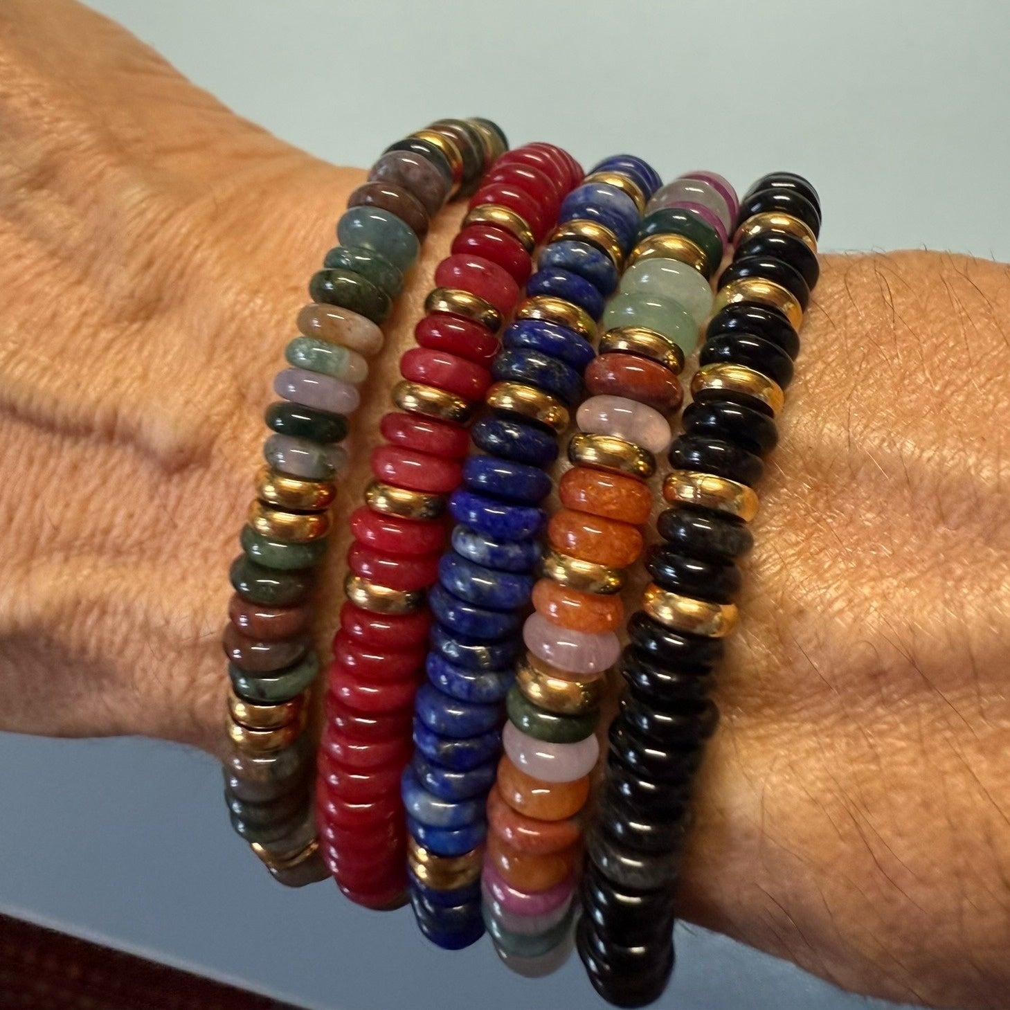 Stretchy bracelets with rainbow and gold rondelle beads worn on the wrist