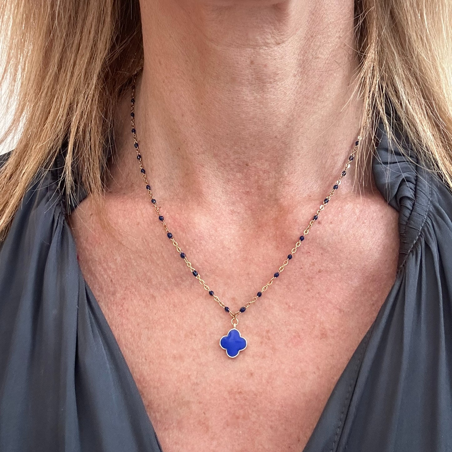 wearing blue rosary gold chain necklace with enamel blue clover charm