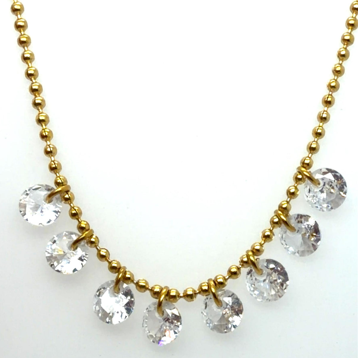 Close up of a necklace made of gold balls in a chain and with 8 sparkly rounded rhinestone crystals in the centre