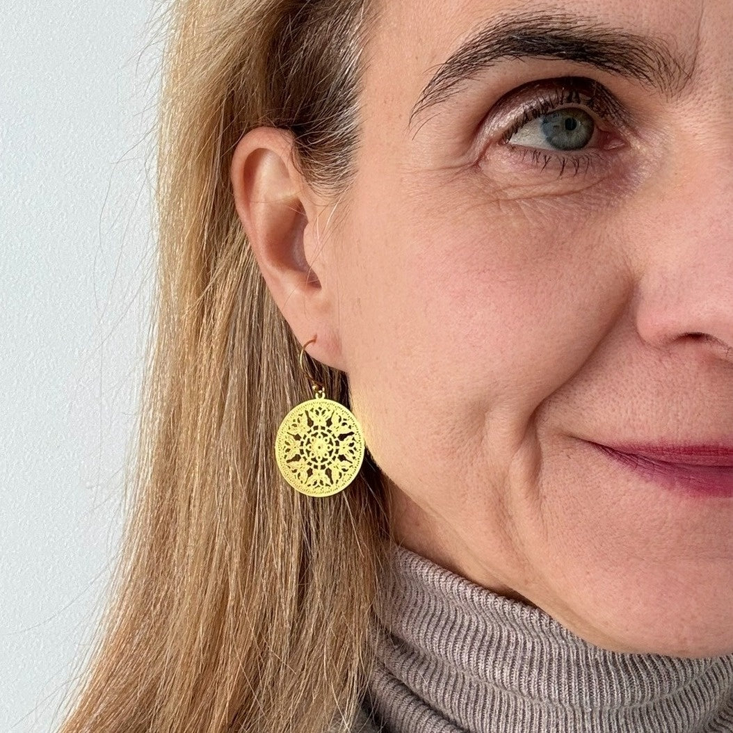 smaller bohemian patterned gold round earrings on model