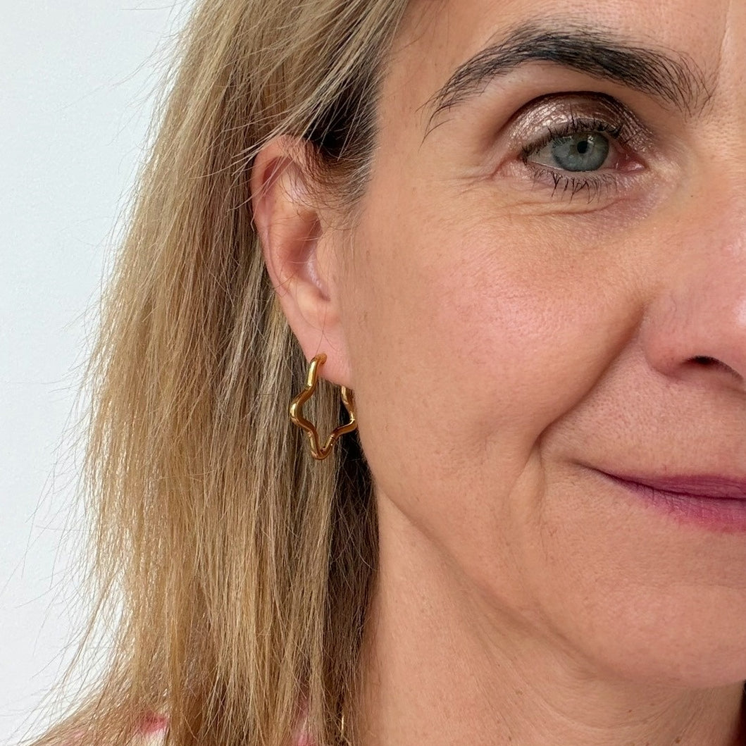 woman wearing gold hoop earrings in the shape of a star