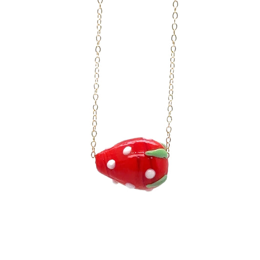 Delicate gold chain necklace with a bright red strawberry glass charm