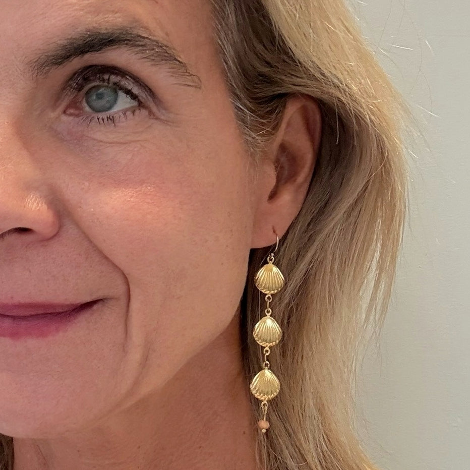 Close-up of a woman wearing gold shell earrings