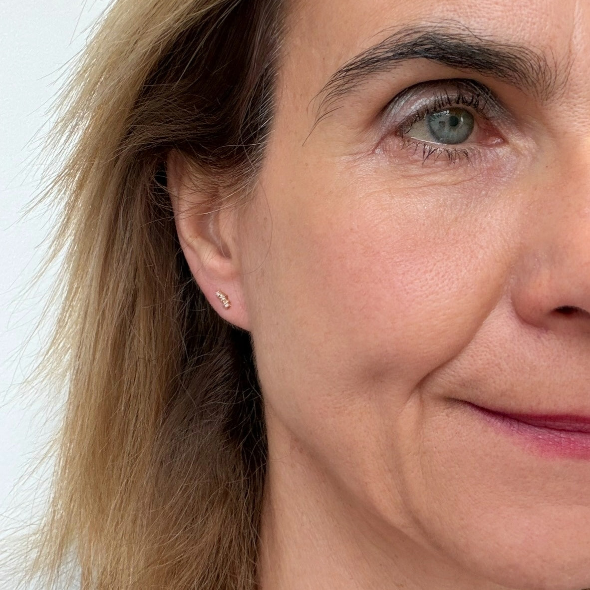Woman wearing small stud earrings with three sparkly stars