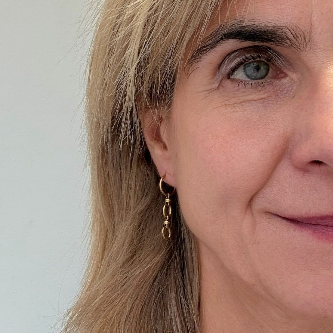 Gold hoops with dangling charm made from two links of a lovely oval chain worn on model