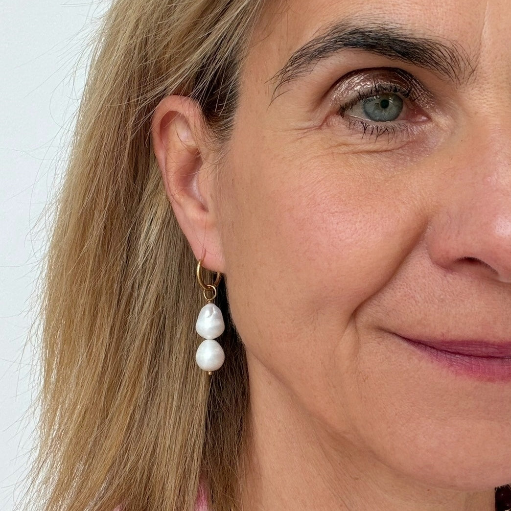 woman wearing gold hoop earrings with two pearl dangling charm
