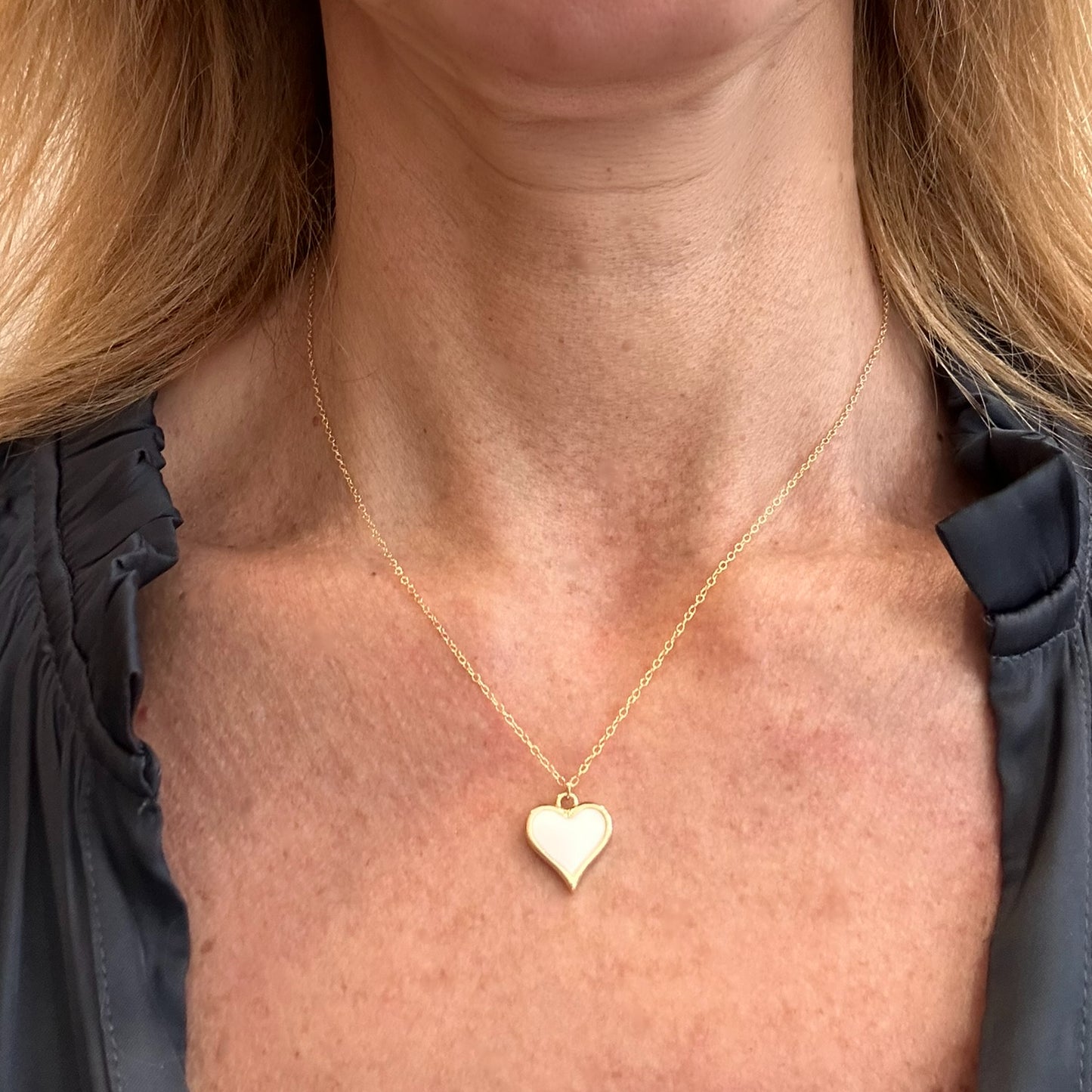 Delicate gold chain necklace with one white enamel heart charm