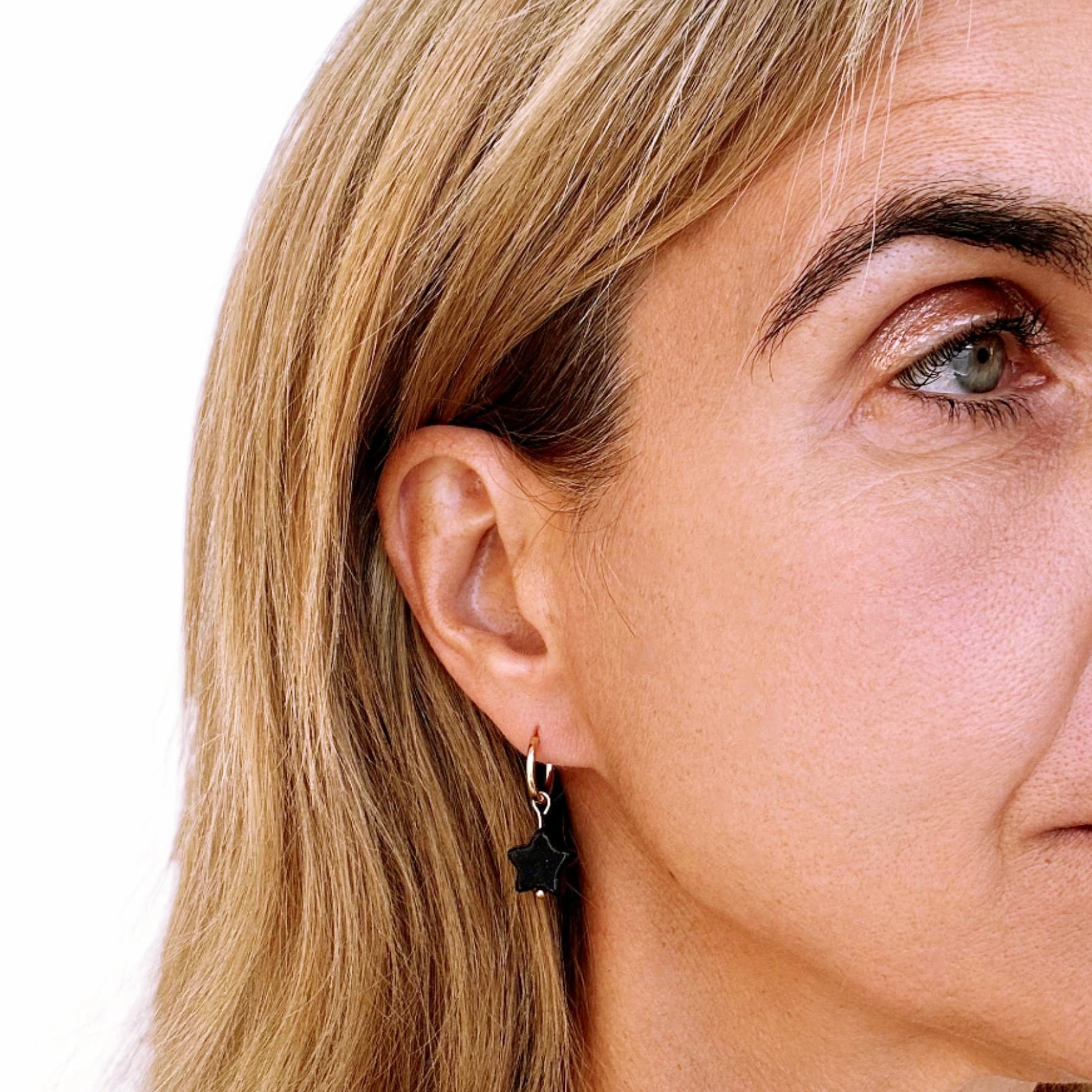 woman wearring gold hoop with midnight dark blue star shaped charm