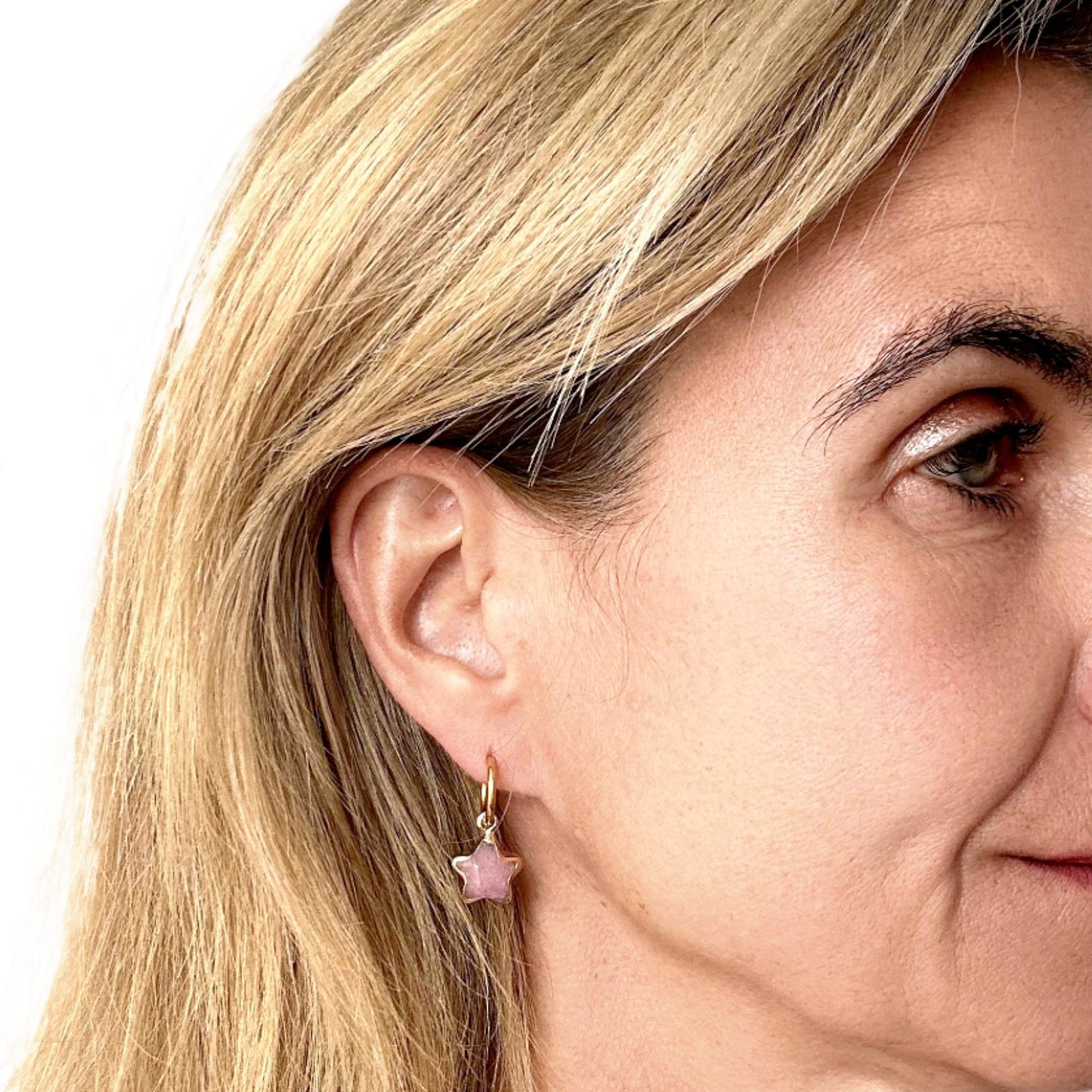 woman wearring gold hoop earring with pink star charm