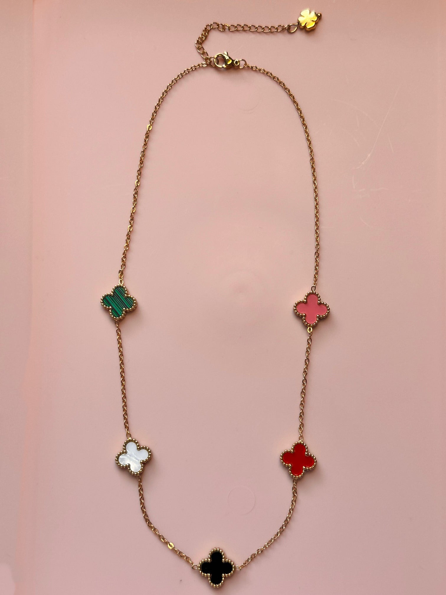 Gold chain necklace with five small clover charms in a rainbow of colours 