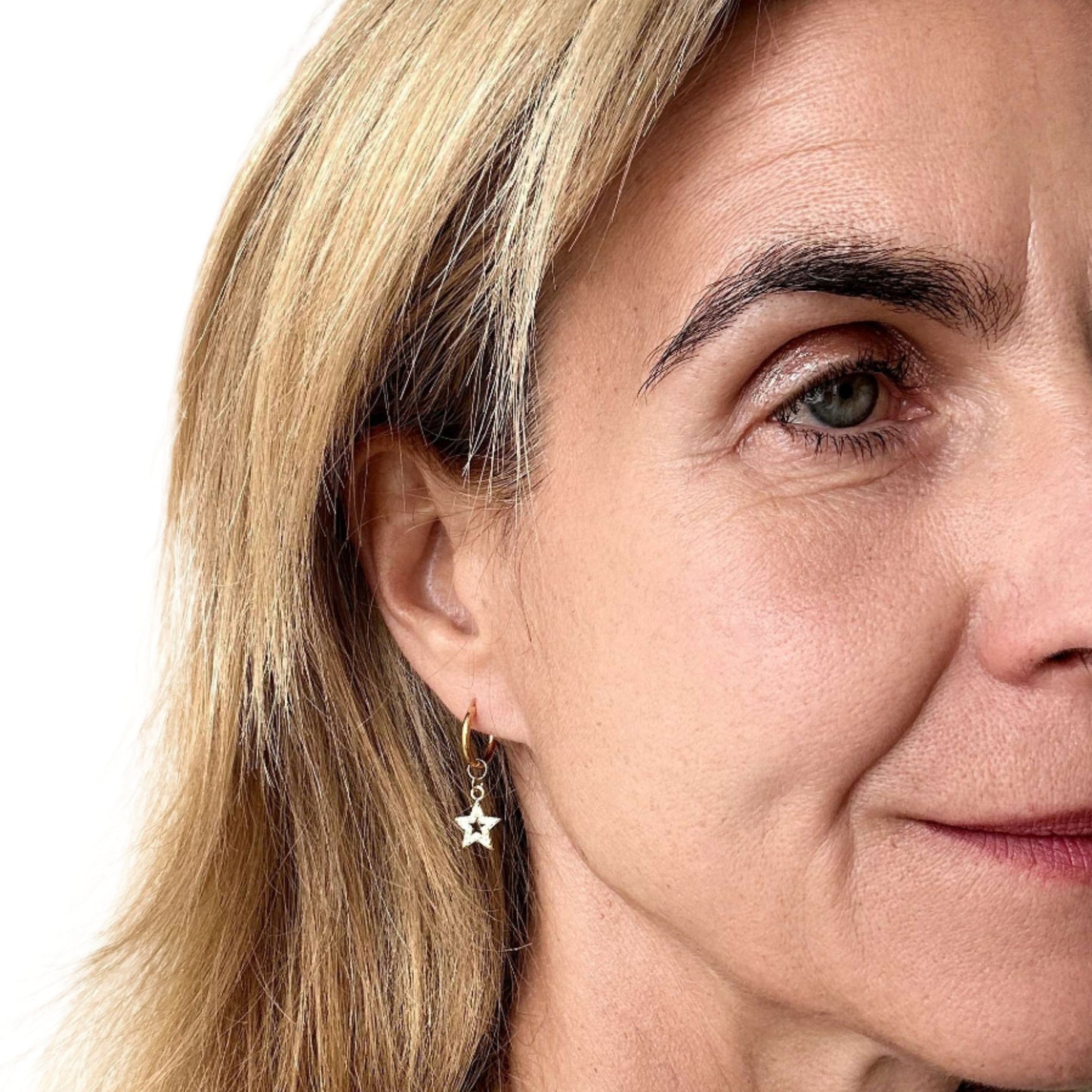 Woman wearring gold hoop earring with sparkly star charm