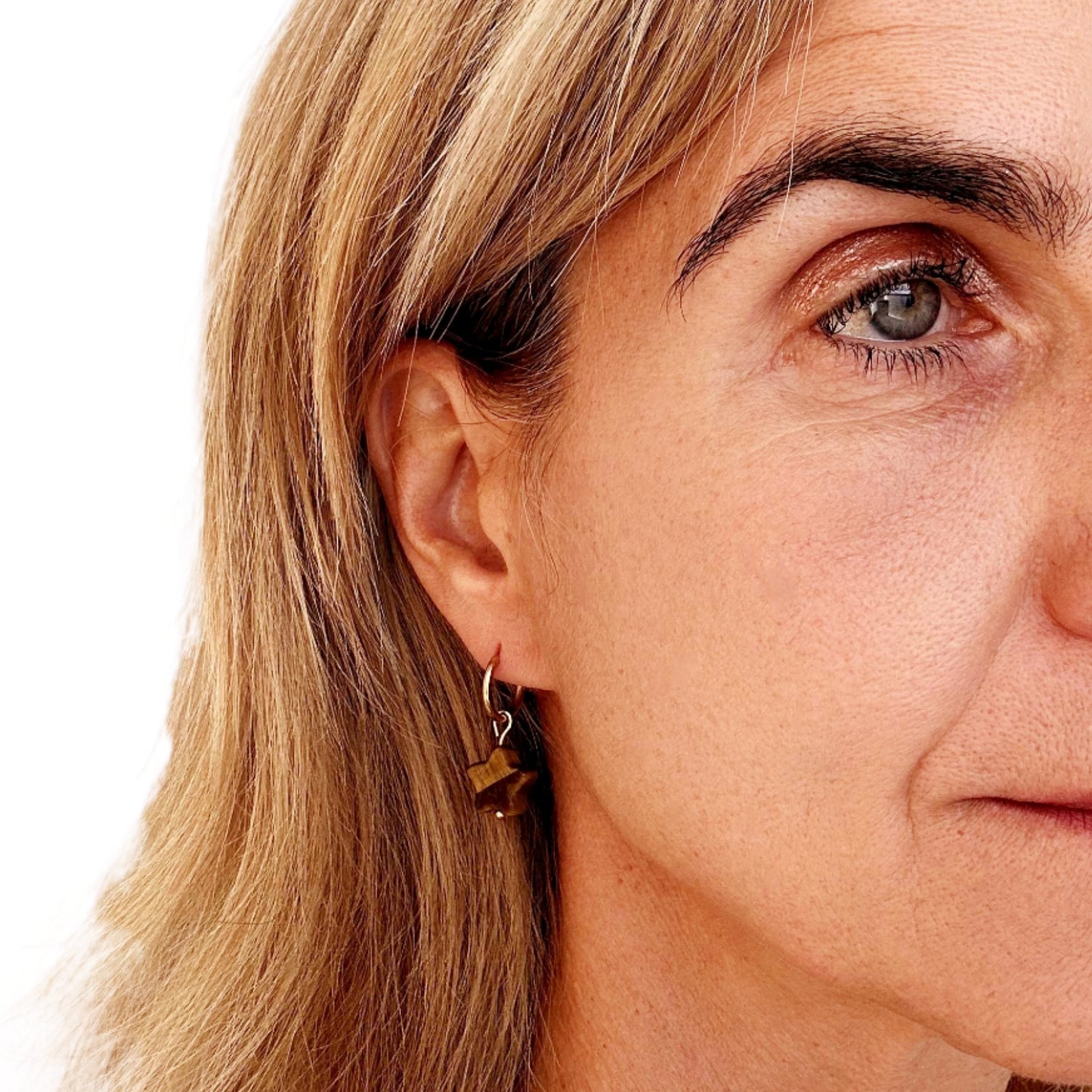 woman wearring gold hoop earrings with star shaped natural Tiger Eye stone charms