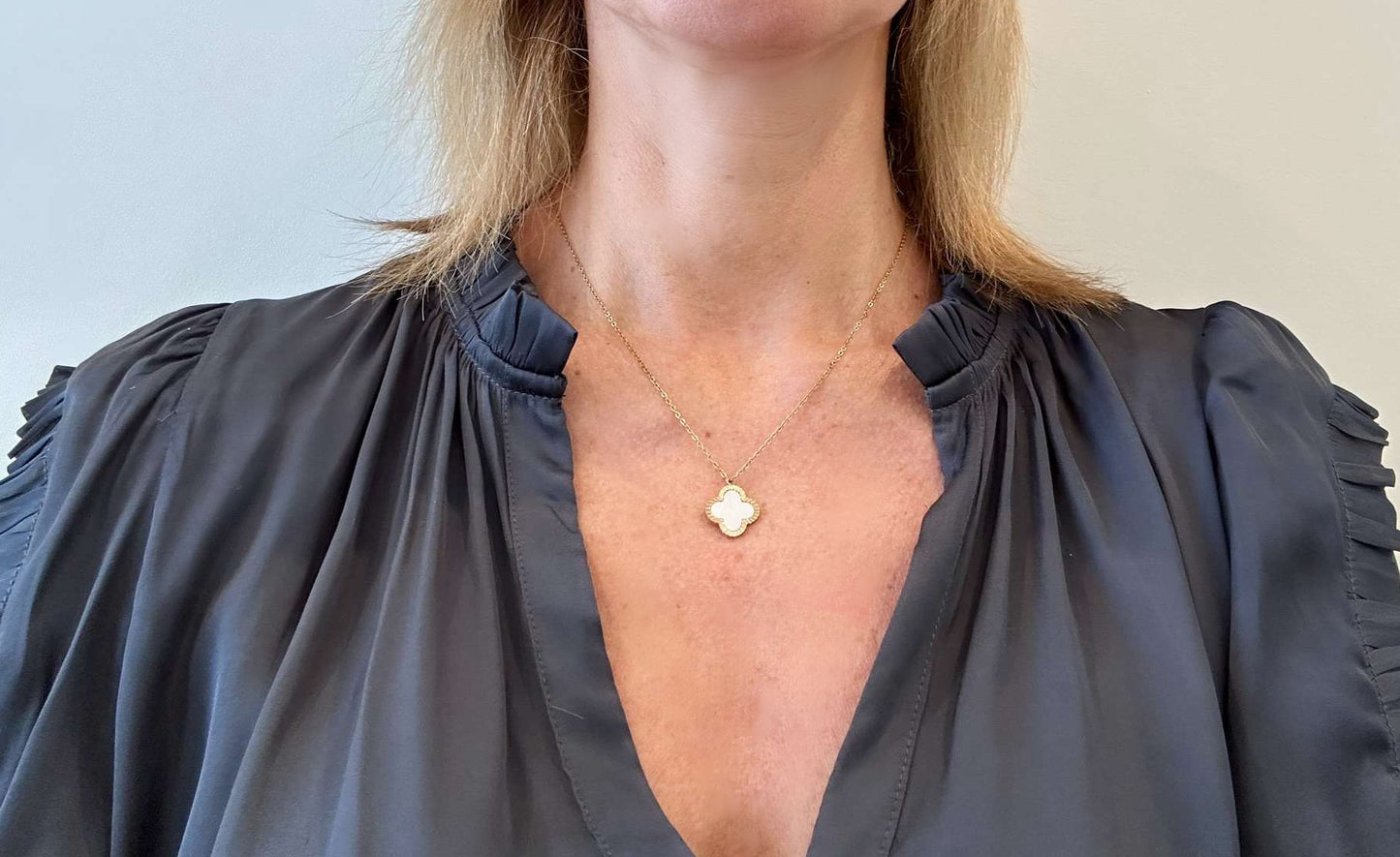 wearing necklace with mother of pearl and gold clover charm pendant